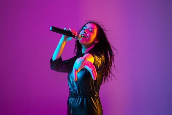 caucasian-female-singer-portrait-isolated-purple-studio-background-neon-light (2)-min