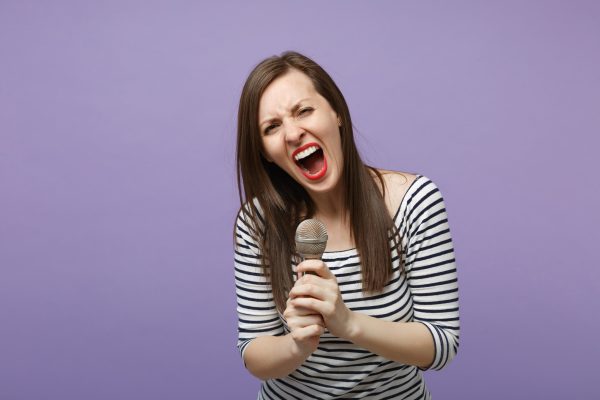 young-brunette-woman-girl-casual-striped-clothes-posing-isolated-violet-purple-background-studio-portrait-people-sincere-emotions-lifestyle-concept-mock-up-copy-space-sing-song-microphone-min